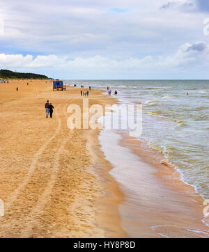 De fortes vagues sur un jour nuageux orageux baignée par la côte de la mer Baltique. Peu de touristes à pied le long d'une plage de sable de la station balnéaire de Palanga, Lituanie, Banque D'Images