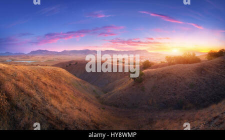 Paysage de montagne et de ciel bleu avec des nuages colorés au coucher du soleil. Soirée exceptionnelle dans la vallée de montagne en été. Vue sur les collines couvertes d'herbe jaune, Banque D'Images