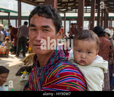 Père avec son enfant sur son dos à l'open market à Punakha, Bhoutan. Banque D'Images