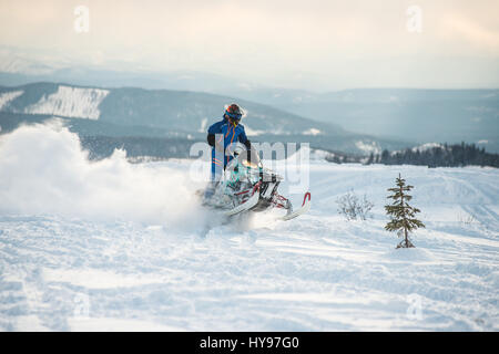 Rider sur la motoneige dans les montagnes Banque D'Images