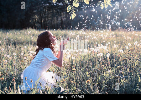 Teen girl blowing seeds à partir d'une fleur de pissenlit spring park Banque D'Images