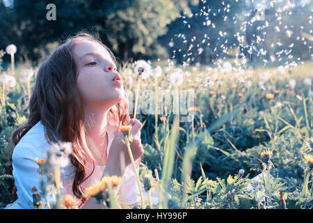 Teen girl blowing seeds à partir d'une fleur de pissenlit spring park Banque D'Images