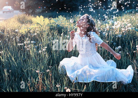 Teen girl blowing seeds à partir d'une fleur de pissenlit spring park Banque D'Images