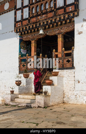 Un jeune moine bouddhiste sur les marches d'un temple au monastère de Talo Talo, le Bhoutan. Banque D'Images