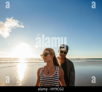 Portrait de beau jeune homme avec sa belle petite amie sur la plage au coucher du soleil. Jeune couple au bord de la mer. Banque D'Images