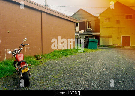 Une moto est garée sur une allée de gravier en Alaska avec orange film filtre dans l'angle donnant la photo un vintage grunge. Banque D'Images