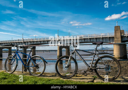 Bicyclettes leaning on railing, Firth of Forth, à Kincardine et ponts Clackmannan par beau jour de printemps, Fife, Scotland, UK Banque D'Images