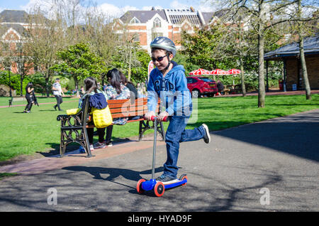 Un jeune garçon équitation un push scooter dans le parc. Banque D'Images