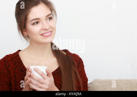 Très belle jeune fille blonde dans un rouge assis sur un canapé dans un salon de beauté. Banque D'Images