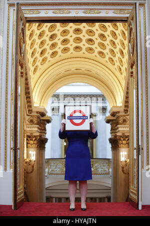 Un membre du personnel est titulaire d'un London Underground sign présenté à la reine Elizabeth II lors de sa visite à la station de métro Aldgate East en 2010, au cours d'un essai pour l'exposition des cadeaux royaux, qui fait partie de l'ouverture d'été annuel de l'État chambres à Buckingham Palace, Londres. Banque D'Images