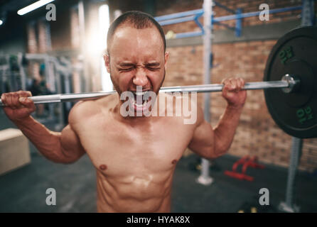 Man lifting barbell in health club Banque D'Images