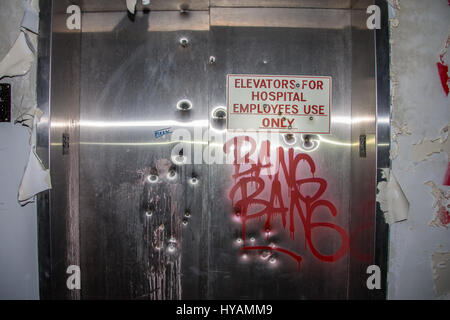 DETROIT, MICHIGAN : un vétéran de combat utilisé ses compétences de l'armée de pénétrer dans un hôpital, il décrépite a même été abandonné par les gangs locaux. Les images montrent comment cette années 60 qui était un célèbre hôpital communautaire est partiellement immergé dans l'eau glacée, Brown a portes criblée de trous de balle et est couvert de graffitis agressifs qui se lit "bang, bang", "Vous êtes le prochain" et "N'ouvrez pas mort à l'intérieur". Soldat de l'armée américaine devenu photographe Robert Johnson (40) ont bravé le criminel potentiellement infestés au sud-ouest de l'hôpital de Detroit à prendre les coups extraordinaires. Banque D'Images