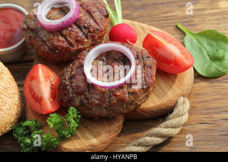 Burger de boeuf à l'oignon et la sauce on cutting board Banque D'Images