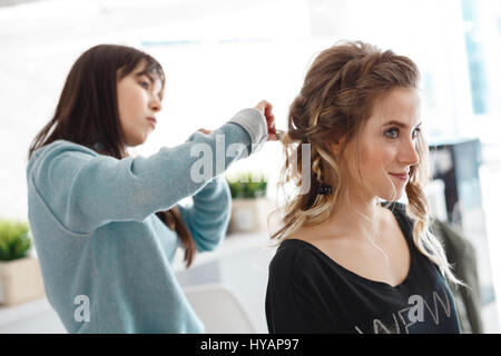 Kiev, Ukraine - 3 mars, 2017 : tressage de cheveux coiffeur professionnel des clients. Coiffure haute création des processus pour le salon de coiffure. Banque D'Images