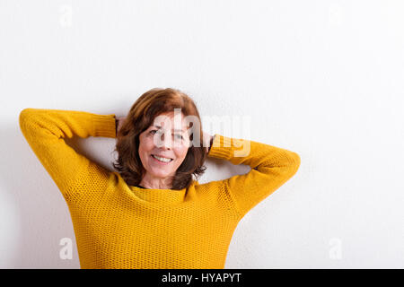 Senior woman in pull en laine jaune, studio shot. Banque D'Images