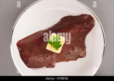 Portrait d'un foie de veau cru isolé sur blanc à frire avec du beurre et du persil Banque D'Images