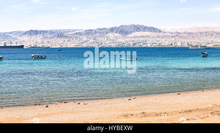 AQABA, JORDANIE - février 23, 2012 : plage urbaine d'Aqaba et d'Eilat voir la ville en arrière-plan en hiver. La Jordanie pays n'a qu'une sortie en mer à bord Banque D'Images