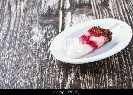 La fraise fait maison et granola ice pop sur la plaque blanche Banque D'Images