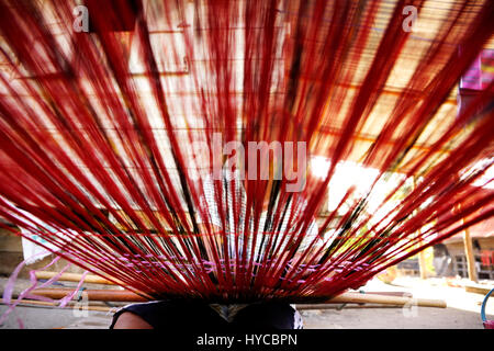 Femme tissant fils rouges avec les mains sur le tissage d'un terminal low angle view dans Flores Samosir. Banque D'Images