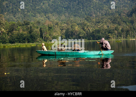 Or jaune chien assis sur un bateau qui descend la rivière à la maîtrise et au pêcheur qui est l'aviron le bateau dans la matinée. Banque D'Images