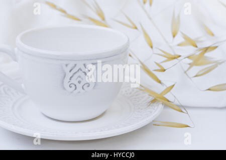 Élégant blanc tasse de thé avec soucoupe, plantes sèches, wild oats, tissu de coton blanc, portant le titre de l'image pour l'image sociale, blogging, marketing Banque D'Images