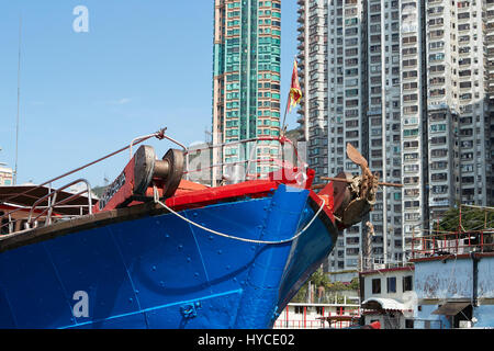 La pêche commerciale peint de couleurs vives, des bateaux amarrés dans le canal d'Aberdeen, des tours d'habitation sur l'île de Hong Kong derrière. Banque D'Images