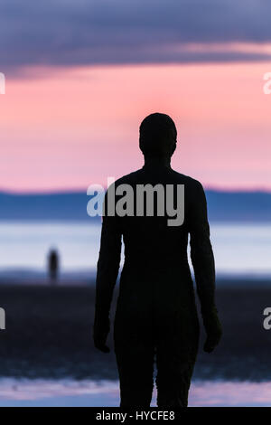 Le coucher du soleil chaud laisse place à crépuscule sur Crosby Beach, accueil de 100 statues en fonte de taille moyenne de la vie. Un autre modèle peut être vu dans la distance plus près de Banque D'Images