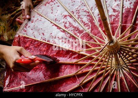 Femme Asiatique peinture mains un papier et bambou parapluie avec couleur rouge Banque D'Images