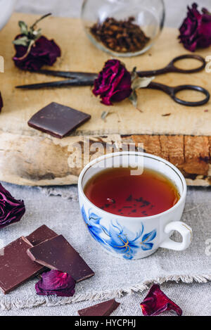 Tasse de thé avec barre de chocolat et boutons de rose. Banque D'Images