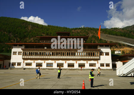 Bâtiment de l'aéroport vu du tarmac de l'aéroport de Paro, avec des employés et des personnes à bord de l'avion, Drukair Bhoutan Banque D'Images