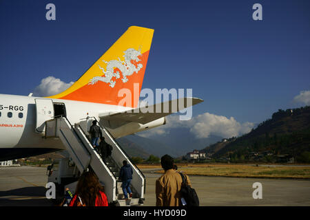 Les passagers d'Drukair Compagnie aérienne royale du Bhoutan Airbus A319 à l'aéroport de paro paro Dzong château à l'arrière, le Bhoutan Banque D'Images