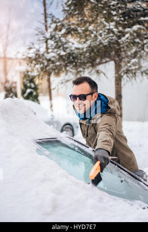 Le nettoyage d'un homme couvert de neige en plastique avec grattoir à neige glace Banque D'Images