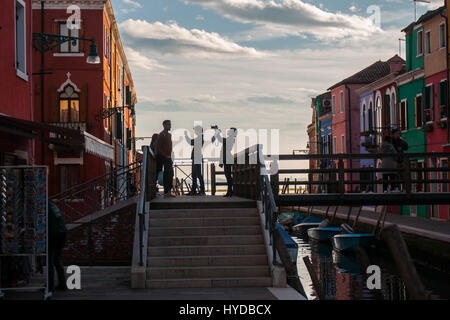 Une vue sur le canal et les maisons colorées avec silhouette de personnes sur le pont dans l'île de Burano, Venise, Italie. Banque D'Images