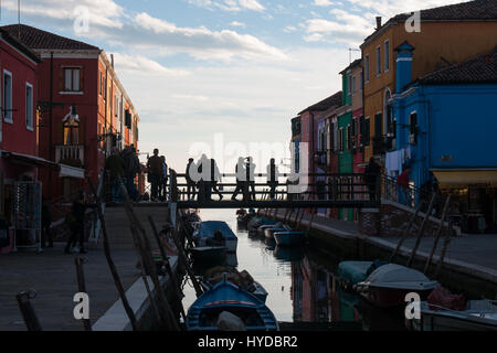 Une vue sur le canal et les maisons colorées avec silhouette de personnes sur le pont dans l'île de Burano, Venise, Italie. Banque D'Images