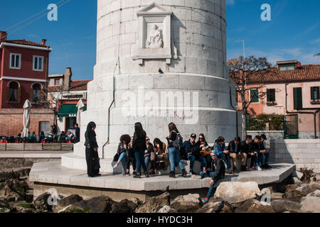 Un groupe de jeunes touristes reste sur le phare de l'île de Murano, Venise, Italie. Banque D'Images