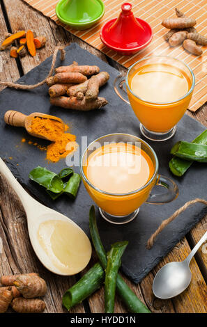 Boisson chaude à l'aloe vera et le curcuma. Tasses en verre sur un plateau d'ardoise Banque D'Images