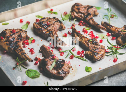 Côtes d'agneau grillées aux herbes et graines de grenade dans le bac Banque D'Images