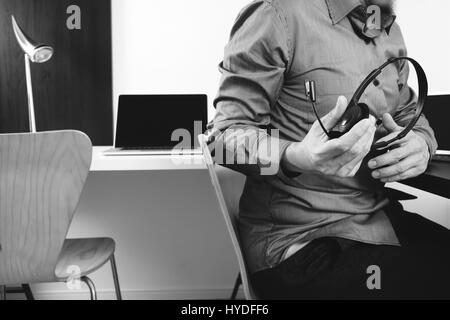 L'homme à l'aide de VOIP casque avec ordinateur portable et tablette numérique comme la communication concept,elle,support centre d'appels et customer service help desk Banque D'Images