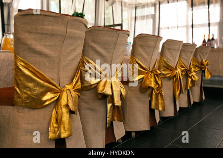 Chaise Mariage Décoration. Couverture beige et or s'incline sur le dos des chaises. Photo horizontale Banque D'Images