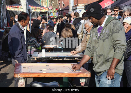 Londres, Royaume-Uni - Octobre 23, 2011 : Les clients de jouer un jeu de table Corrom at a market stall dans Brick Lane street marché aux puces Banque D'Images