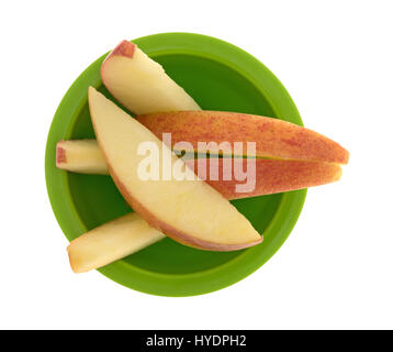 Vue de dessus quelques tranches de pomme rouge dans un petit bol vert isolé sur un fond blanc. Banque D'Images