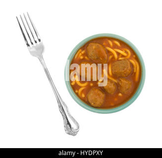 Vue de dessus d'une portion de spaghetti et boulettes de viande dans un bol avec une fourchette pour le côté isolé sur un fond blanc. Banque D'Images