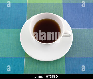 Thé noir décaféiné dans une tasse blanche avec une soucoupe sur un tapis coloré. Banque D'Images