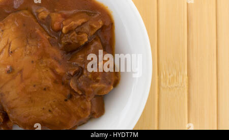 Haut fermer voir d'une boule blanche avec une portion de filet de Tilapia dans une sauce marinara sur un napperon en bois. Banque D'Images