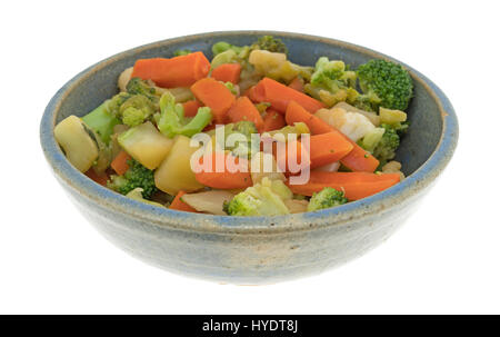 Un vieux bol en grès rempli de carottes, brocoli et chou-fleur en sauce isolé sur un fond blanc. Banque D'Images