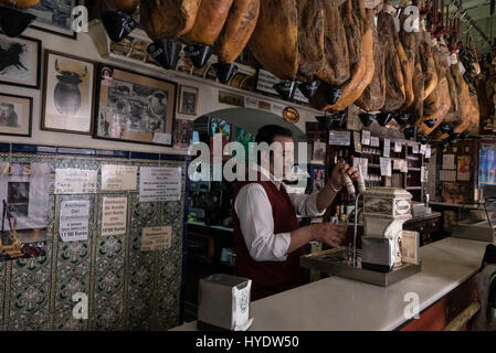 Un rack de mountain air Jamon Serrano ( jambon épaule ou jambon espagnol salés à sec) accrocher dans une ligne au-dessus d'un bar dans la vieille ville de Séville, Sevil Banque D'Images
