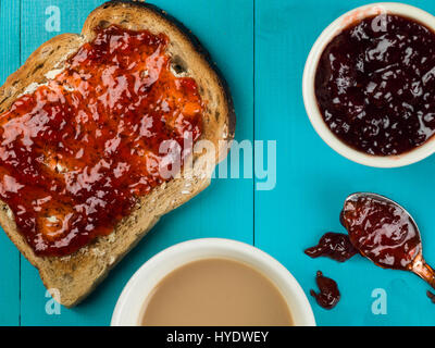 La confiture de fraise ou de préserver sur tartines beurrées contre un fond bleu Banque D'Images