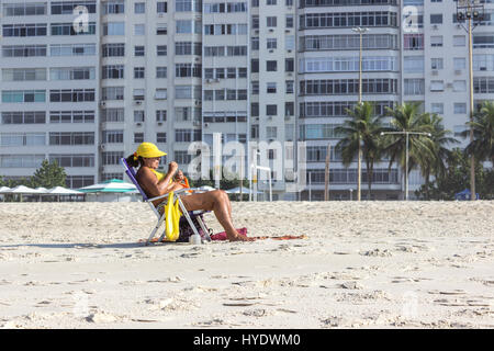 Brésil, Rio de Janeiro : Dame coin sur une chaise de plage et faire ses ongles sur Leme Banque D'Images