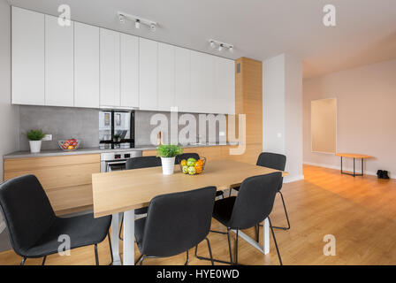 Cuisine ouverte avec table, chaises, placards en bois blanc et les panneaux de plancher Banque D'Images