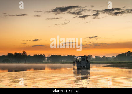 Seul bateau sur l'eau jaune billabong en lumière d'Aube dorée, Territoires du Nord, Australie Banque D'Images